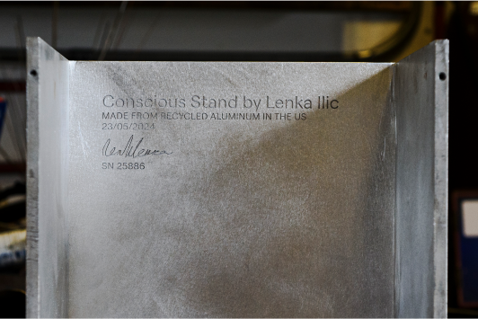 Flat surface of sanded raw aluminum shows debossed authenticity mark stating name of the collection, made of recycled aluminum in the US, designer’s signature, date, and a serial number.
